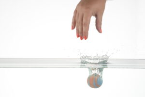 Product photography image of a bath bomb dropping into water with a big splash.